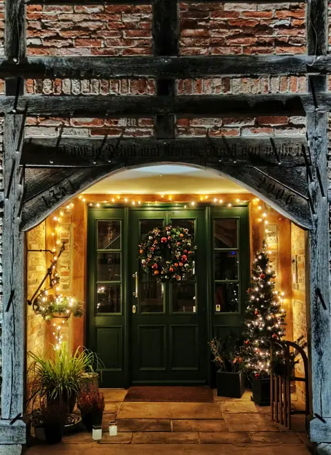 Front door decorated with a wreath and lights