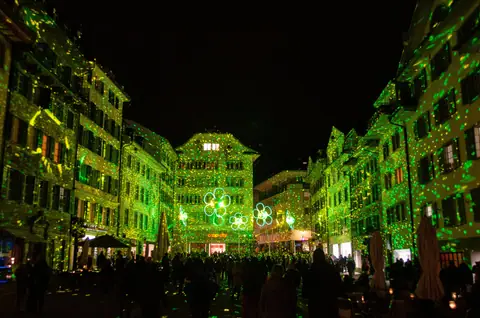 Green laser dots across building fronts on a town square