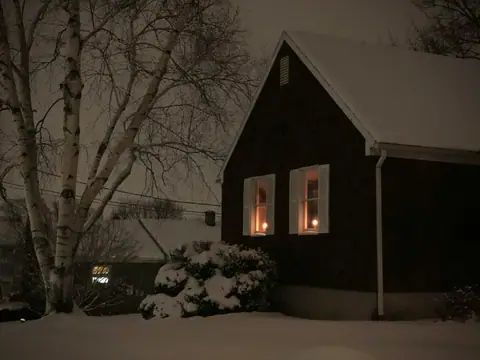 Snowy house at night with candles in the windows